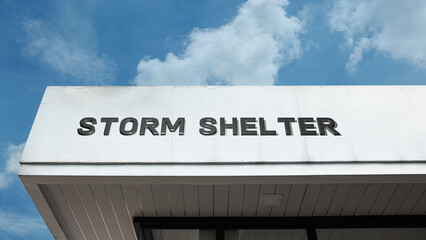Fototapeta premium Storm Shelter word signage on a sturdy institutional building under a blue sky, symbolizing safety, emergency preparedness, resilience, severe weather protection, refuge, and disaster readiness