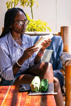 A beautiful young African woman reading a book outdoors