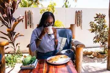 A young African woman enjoying toast and coffee for breakfast