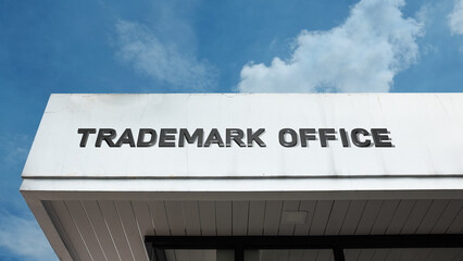 Obraz premium Trademark Office word signage on a government or legal building under a blue sky, symbolizing intellectual property, branding, legal protection, registration, regulation, and business law