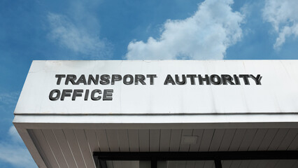 Obraz premium Transport Authority Office word signage on a government or regulatory building under a blue sky, symbolizing public service, transportation governance, infrastructure, regulation, and urban planning