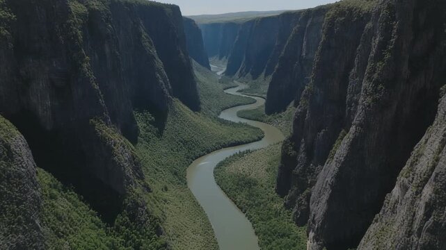 Aerial perspective following a snaking river gorge with towering sheer cliffs rising dramatically on each side