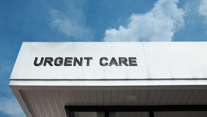 Urgent Care word signage on a medical clinic building under a blue sky, symbolizing immediate healthcare access, walk-in service, non-emergency treatment, and prompt medical aid
