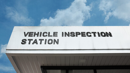 Vehicle Inspection Station word signage on a regulatory building under a blue sky, symbolizing automotive safety, emissions testing, compliance, law, and roadworthiness