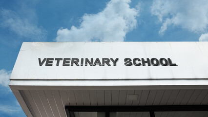Obraz premium Veterinary School word signage on an academic building under a blue sky, symbolizing animal medicine education, health research, professional training, and higher learning
