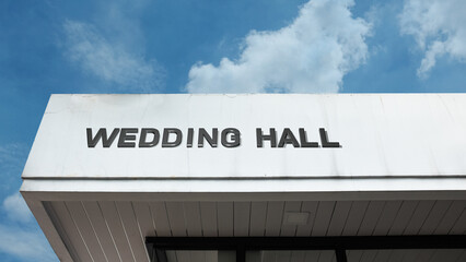Wedding Hall word signage on a festive building under a blue sky, symbolizing marriage, celebration, event venue, ceremony, reception, and romantic gathering space