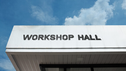 Workshop Hall word signage on an educational building under a blue sky, symbolizing training, learning, construction, collaboration, skills, and industry