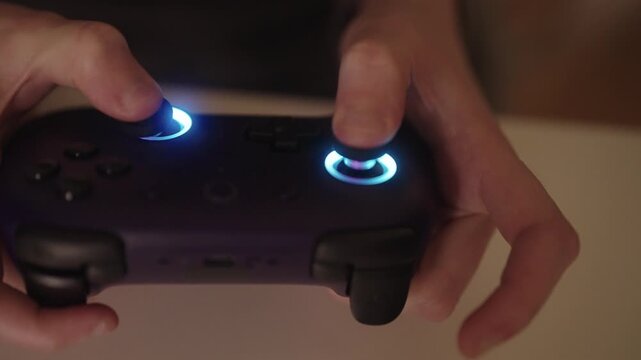 Female hands holding using modern gaming controller with illuminated blue joysticks, engaging in digital entertainment, highlighting immersive gaming and interactive technology, close-up, slow motion.