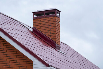 Beautiful brick chimney on a modern house under a cloudy sky during the day