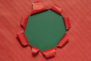 Torn red wrapping paper revealing a green background during holiday gift preparation