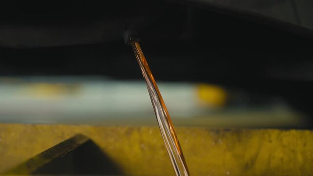 Close-Up of Engine Oil Flowing Into Yellow Drain Pan
