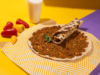 Lahmacun, Turkish Thin flatbread topped with a spicy ground chicken mixture and baked in oven on bright yellow and purple background. Colorful food photography, bright color food image.