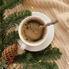 Cup of coffee and fir branches on a knitted background. Christmas still life aesthetic
