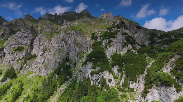 Long horizontal aerial panorama along the steep southwestern face of Scara Peak, revealing hundreds of dramatic limestone erosion towers rising above Gaura Valley in the Bucegi Mountains of Romania