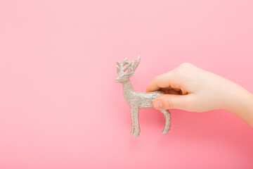 Little child girl hand holding and showing beautiful shiny silver reindeer toy covered with...