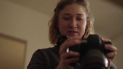 Close-up of young woman living with cerebral palsy holding modern DSLR camera, demonstrating concentration and dedication pursuing passion for photography and artistic expression, slow motion.