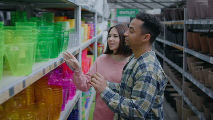 Couple shopping for colorful plant pots in a vibrant store on a sunny day