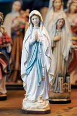 Fototapeta premium Virgin Mary statue figurine with rosary on wooden table