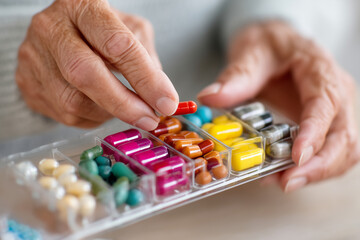 caregiver preparing medication organizer, careful hands sorting pills, home care environment, close-up, 
