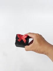 Hand holding a gift box wrapped with a red ribbon on a white background. Black Friday