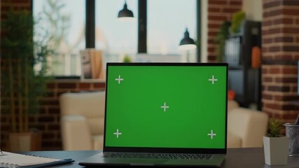 Laptop computer with green screen on modern desk in front of brick wall, workspace mockup for chroma key compositing and design