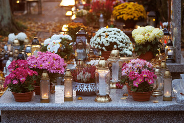 Kwiaty zdobiące nagrobki stanowią symbol pamięci, miłości i szacunku dla zmarłych. Jesienna kolorystyka w połączeniu z naturalnym światłem nadaje fotografii spokojny i nostalgiczny charakter.