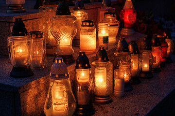 Nastrojowe ujęcie cmentarza po zmroku, gdzie jedynym źródłem światła są palące się znicze. Migoczące płomienie tworzą ciepłą, melancholijną atmosferę, podkreślając duchowy i refleksyjny wymiar miejsca © Michał.S-FOTO