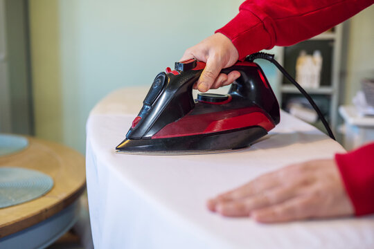 Man's hand ironing clothes on an ironing board at home