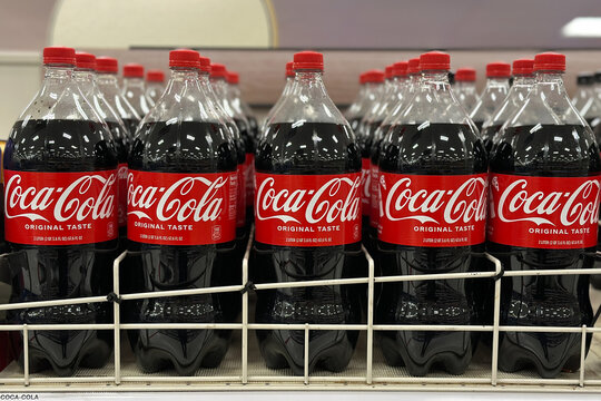 Northville, Michigan, USA - Nov 16, 2025 : A close-up view of multiple Coca Cola 2 liter bottles arranged in a row on a store shelf, showcasing their red labels and neatly organized display.