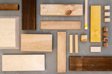 Flat lay of various wood and plywood pieces on concrete texture. Carpentry background.