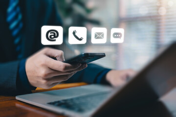 A businessman using a smartphone with floating contact icons, representing digital communication, customer support, online service channels, email, phone, and messaging solutions in modern business.