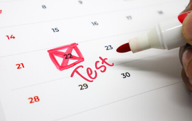 Hand marking Test on a calendar date, highlighting an important upcoming exam or scheduled event with a red marker