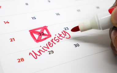 Highlighting a significant academic milestone on a calendar with a red pen, anticipating university admissions or crucial deadlines
