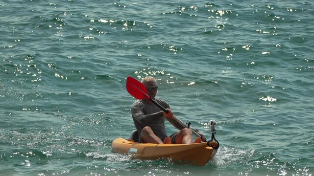 Kayaker paddling ocean, man enjoying a leisure activity in tropical water.