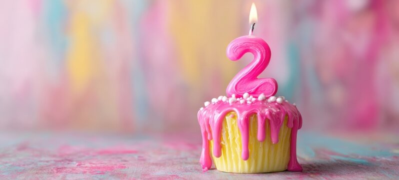 The Cupcake with Pink Dripping Frosting and Lit Number Two Candle on Pastel Background
