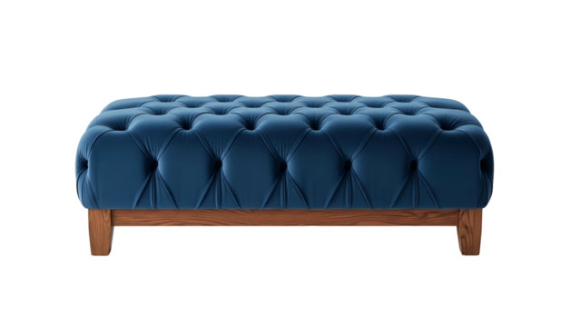 A tufted blue velvet ottoman with wood legs sits isolated on a black background