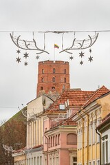A cozy, festive street in Vilnius Old Town with Gediminas tower and Christmas decorations and ornaments creating a charming holiday atmosphere