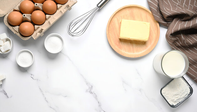 Baking ingredients on white marble background with eggs butter milk and flour