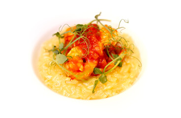 Gourmet risotto dish featuring creamy rice topped with vibrant tomato sauce, succulent shrimp, and fresh microgreens, beautifully presented in a white bowl for culinary delight