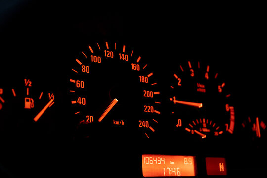 Close up of a speedometer in a car, illuminated with orange light. After edits.