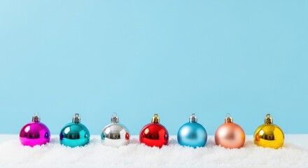 A vibrant array of colorful Christmas baubles nestled on pristine white snow against a soft blue background, evoking festive holiday cheer and winter wonder