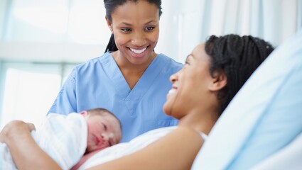 Obraz premium Low angle close-up of a smiling African American nurse in blue scrubs looking down at a happy mother holding a newborn baby in a hospital bed under bright natural light 