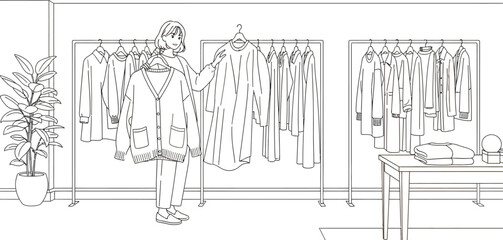 Woman selecting a cardigan from a clothing rack in a minimalist fashion store