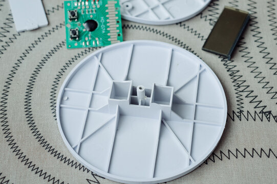 Disassembled electronic device kitchen scales with circuit board wires plastic parts on a table.Useful for articles about electronics repair, DIY projects, device maintenance and engineering tutorials