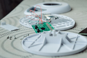 Disassembled electronic device kitchen scales with circuit board wires plastic parts on a table.Useful for articles about electronics repair, DIY projects, device maintenance and engineering tutorials