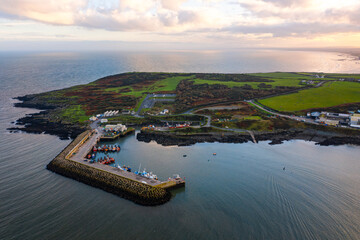 Aerial view of Port Oriel in Clogherhead with fishing boats and hazy evening light along the calm coastline