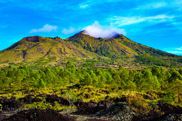 Lush Green Slopes of Mount Batur with Cloud-Covered Peaks and Forest at Kintamani, Bali
