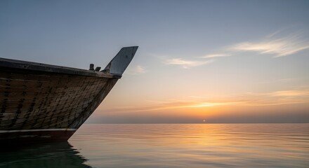 A minimalist composition of a traditional wooden dhow boat's weathered hull against a flat, calm sea at dawn. Evokes tranquility, travel, and Arabian Gulf heritage.