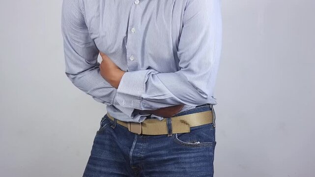 Stomach cramps, stomach aches, and other stomach ailments. A man's hands wrapped around his stomach indicate unbearable pain and injury in the abdominal area. Holding in a bowel movement.
