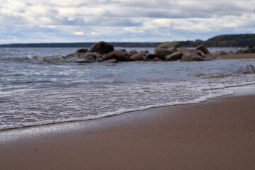 Gentle waves rolling toward sandy coast with visible rocks in foreground.